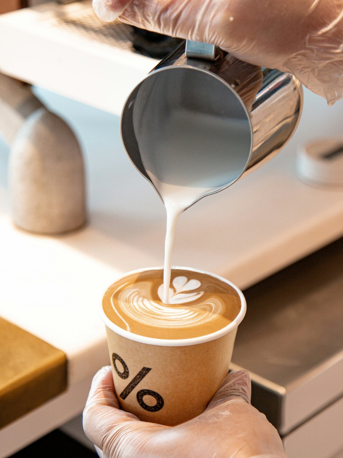 A barista carefully pouring latte art into a cup