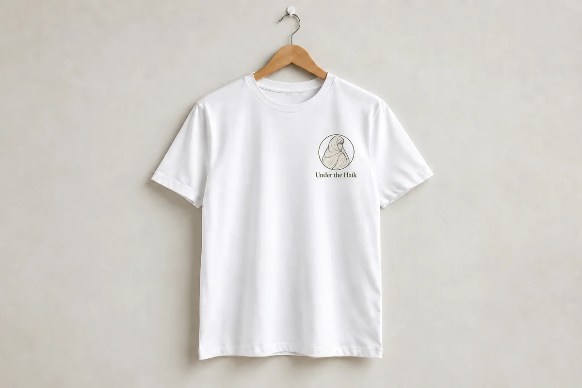 White staff T-shirt with a small Under the Haik logo and name on the left chest